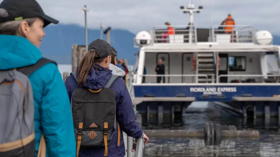 Hikers approaching the Fiordland Express, Milford Track Water Taxi, at the dock, ready for their journey.