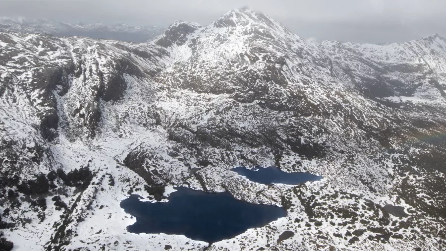 Aerial view of snow-dusted alpine peaks and glacial lakes in Fiordland National Park in winter