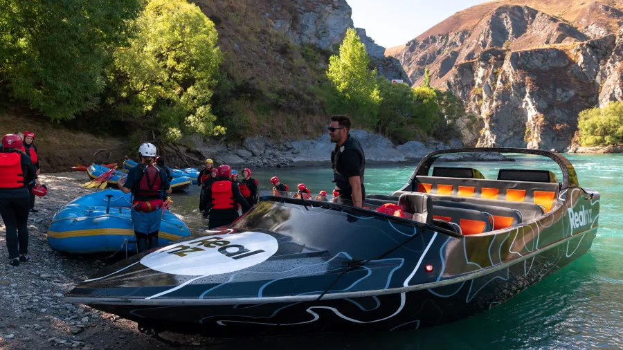 Jet boat and rafting group preparing to switch activities on the riverbank