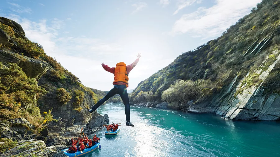 Rafter leaping off a cliff into the Kawarau River during an adventure tour