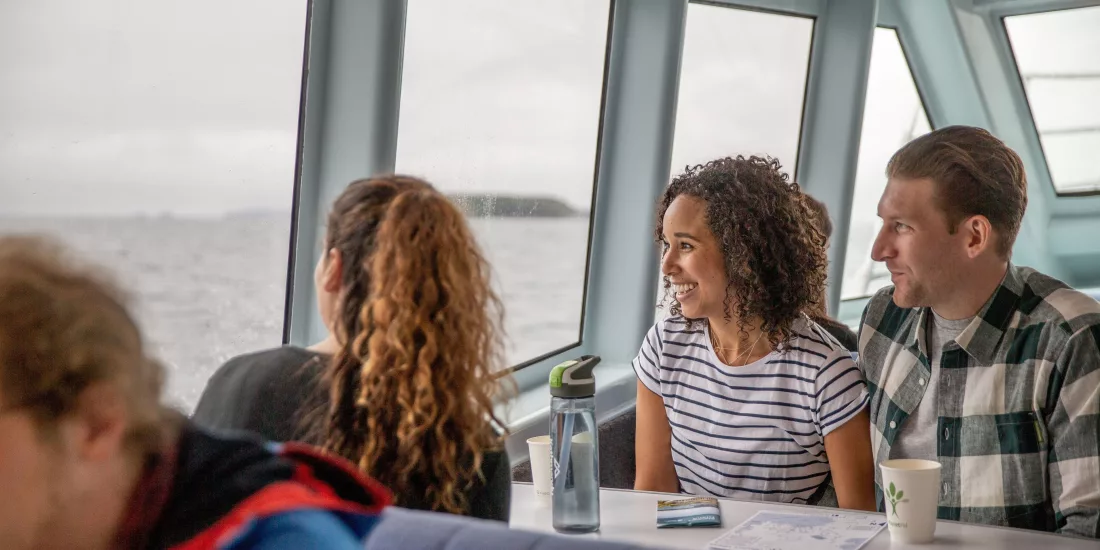 Passengers enjoy the scenic ferry ride to Stewart Island, gazing out the window at the ocean.