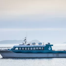 The Foveaux Express ferry approaching the dock with Stewart Island's distant coastline in the background.