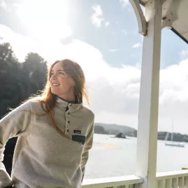 A traveler enjoys the view as they travel to Stewart Island aboard the ferry, gazing at the scenic coastal landscapes of Oban.