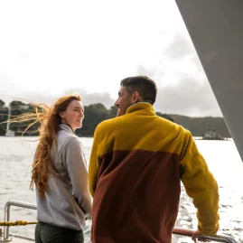 Smiling passengers aboard the Stewart Island ferry, enjoying the scenic views on a bright day.
