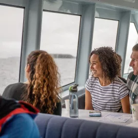 Passengers enjoy the scenic ferry ride to Stewart Island, gazing out the window at the ocean.