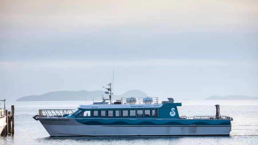 The Foveaux Express ferry approaching the dock with Stewart Island's distant coastline in the background.