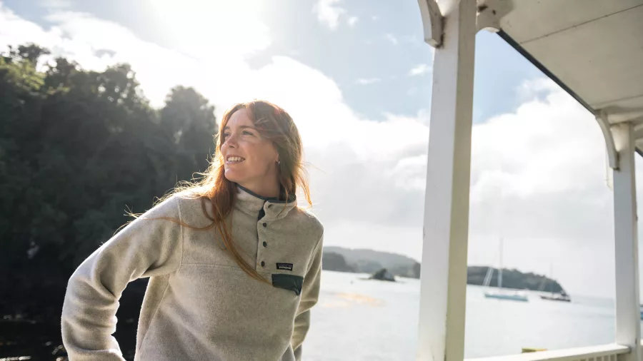 A traveler enjoys the view as they travel to Stewart Island aboard the ferry, gazing at the scenic coastal landscapes of Oban.