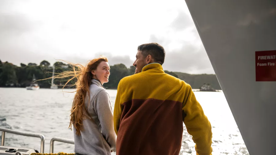 Smiling passengers aboard the Stewart Island ferry, enjoying the scenic views on a bright day.