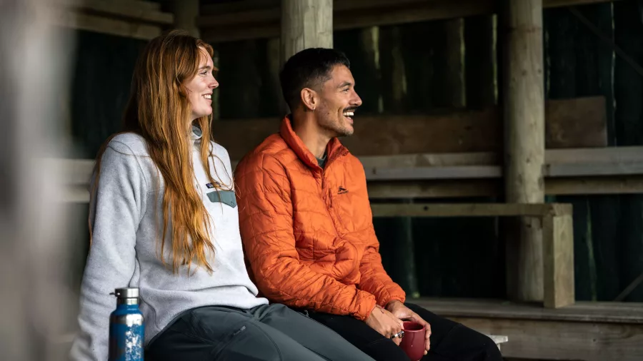 Guests relaxing in a rustic shelter during the Stewart Island Wilderness Walk at The Neck