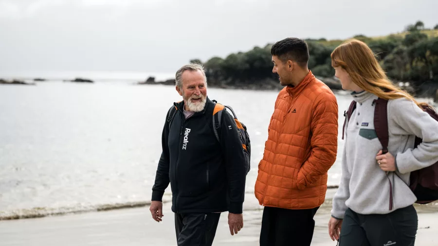 Guide and guests enjoying a beach walk at Oneke on the Stewart Island Wilderness Walk