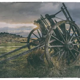 Weathered wagon wheel at sunset in the golden fields of Maniototo