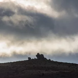 Moody clouds behind an isolated rock formation on a Maniototo ridge