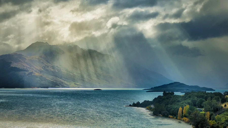 Dramatic sunbeams breaking through stormy clouds over Lake Whakatipu