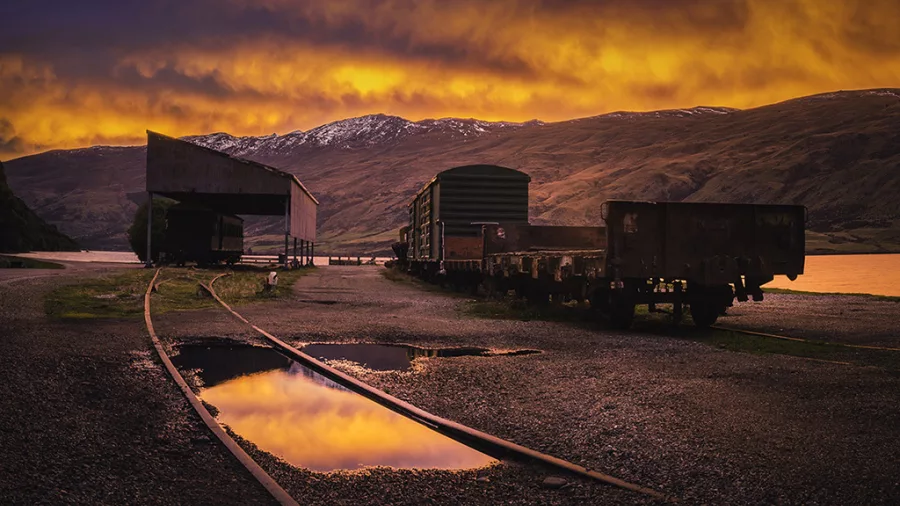 Abandoned train carriages at Kingston Station with sunrise over Lake Whakatipu