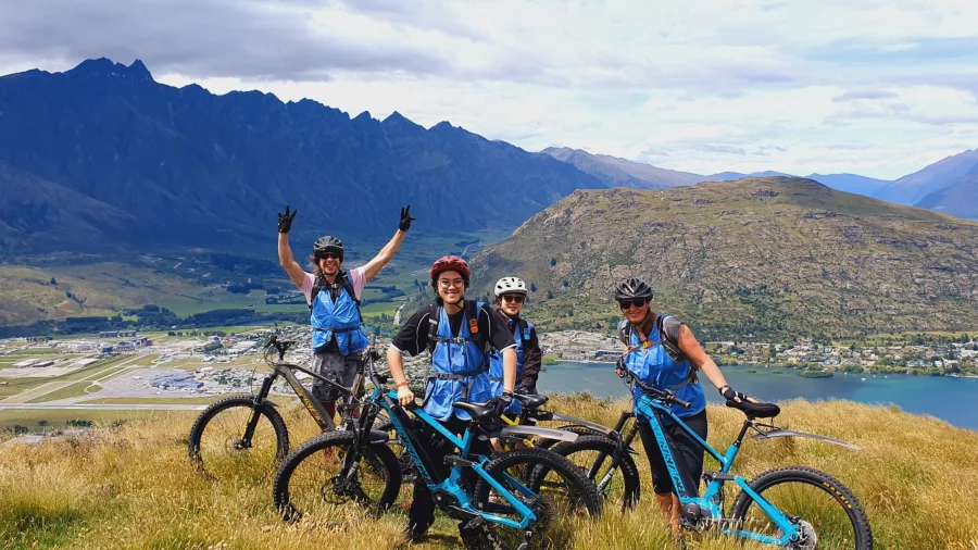 Group of riders with e-bikes above Queenstown Airport and Lake Whakatipu