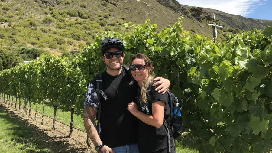 Couple smiling together in lush vineyard on Gibbston wine trail