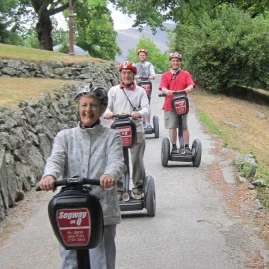 Smiling group riding Segways on a tree-lined Queenstown path