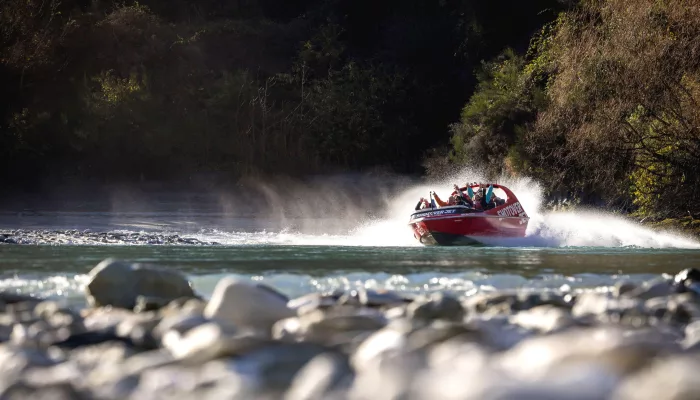 Shotover Jet boat creating spray as it speeds along the Shotover River in Queenstown