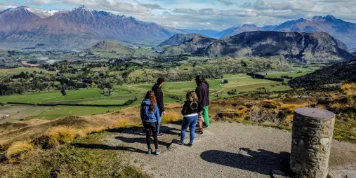 Guided Middle Earth tour group overlooking the green Wakatipu Basin and mountains near Queenstown