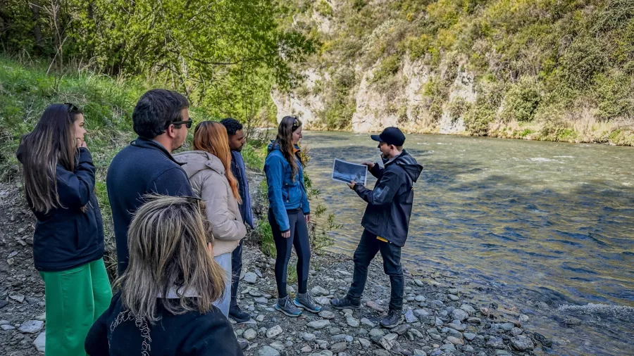 Guide showing LOTR film stills to a group by the Arrow River