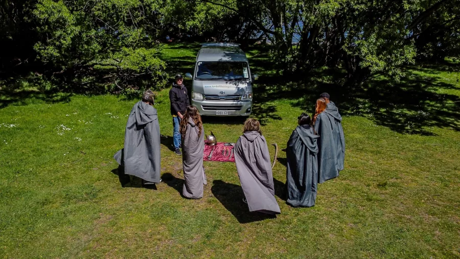 Group in cloaks gathered for a LOTR-style costume briefing beside the tour van