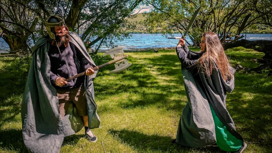 Guests in costume acting out a sword battle by the lake on a LOTR tour