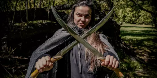 Tour guest posing with two replica swords during a Middle Earth experience in Queenstown