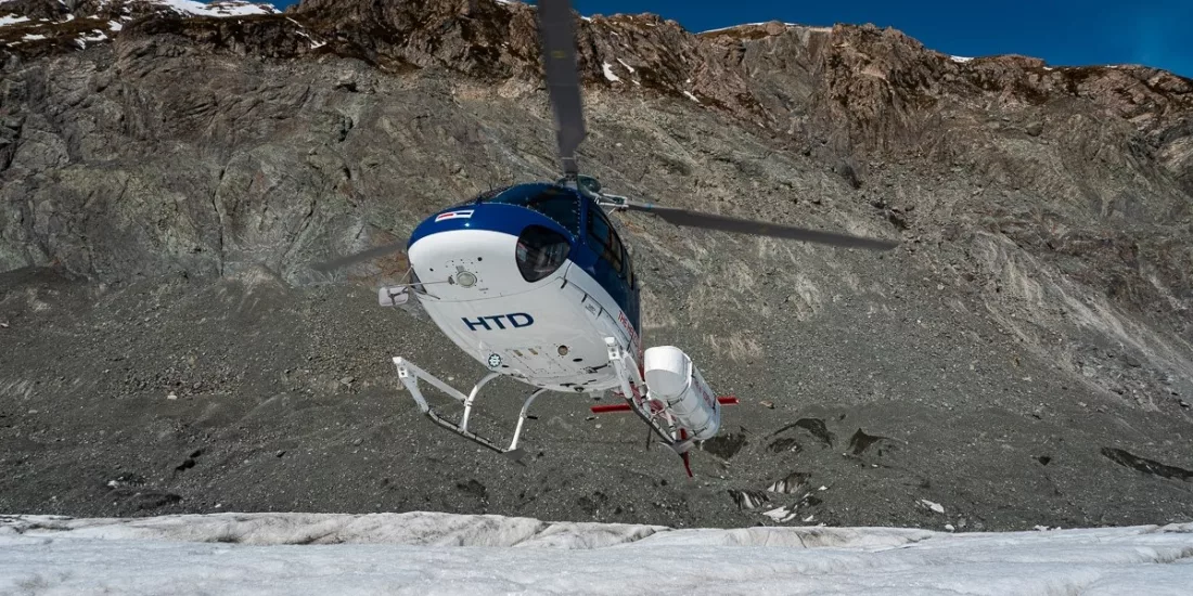 Helicopter touching down on glacier ice field