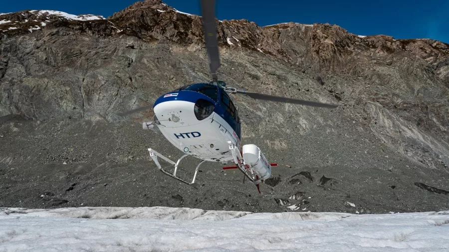 Helicopter touching down on glacier ice field
