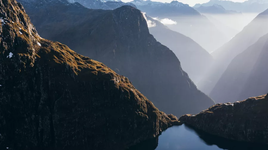 Sunlight streams through the mountains over Milford Sound in Fiordland, New Zealand