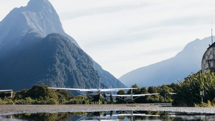 Small aircraft parked at Milford Sound with a striking mountain reflection