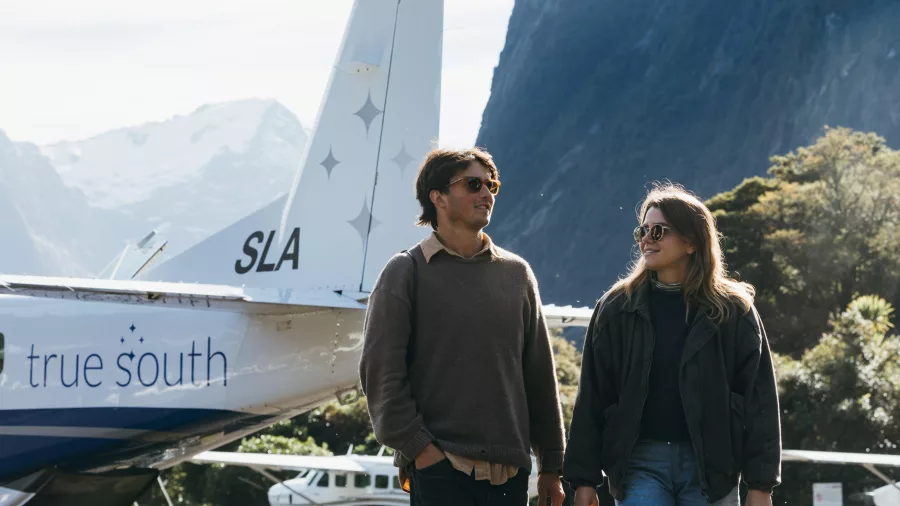 Couple walking away from a True South aircraft at Milford Sound airstrip