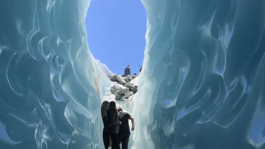 Group exiting a sculpted ice cave tunnel on the Tasman Glacier near Mount Cook