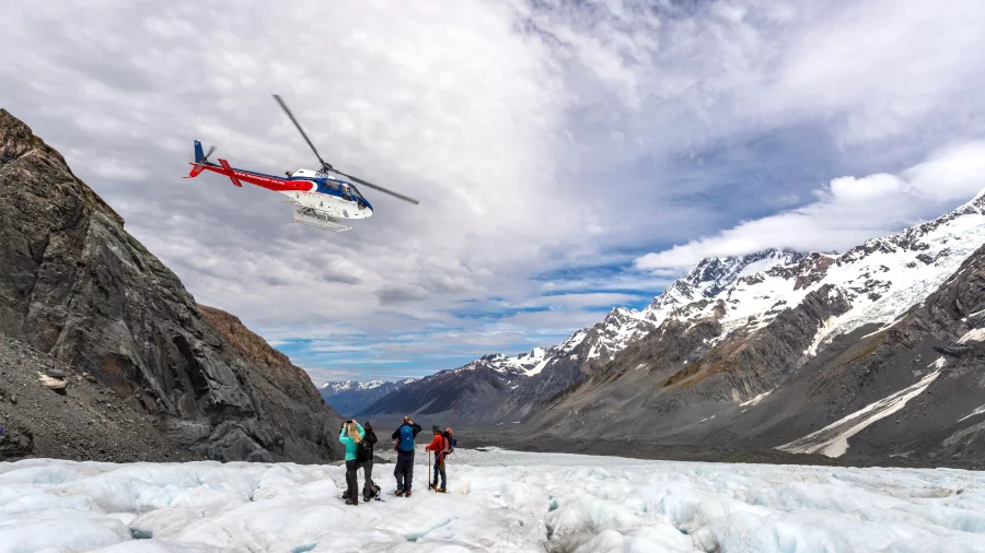 Helicopter landing on the Tasman Glacier with group of hikers ready to explore