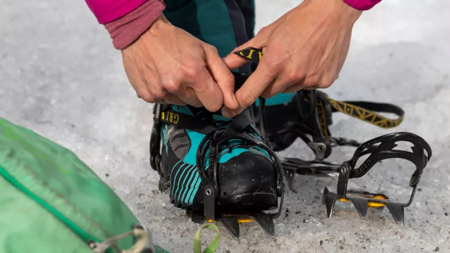 Person strapping crampons to hiking boots on the Tasman Glacier