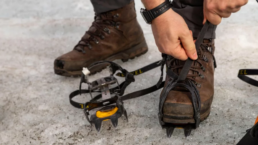 Close-up of crampons being secured to hiking boots on a glacier hike