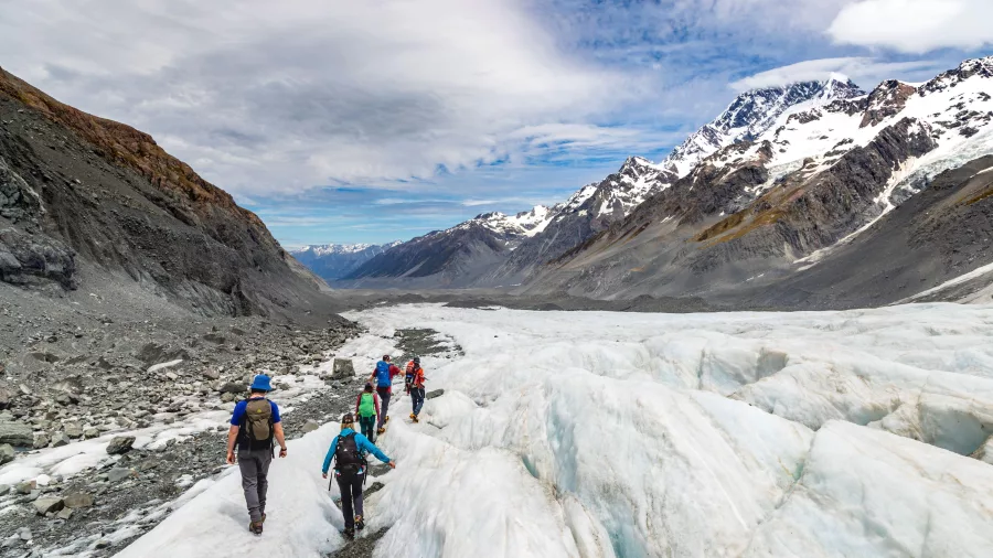 Guided hikers approaching the edge of the Tasman Glacier near the moraine