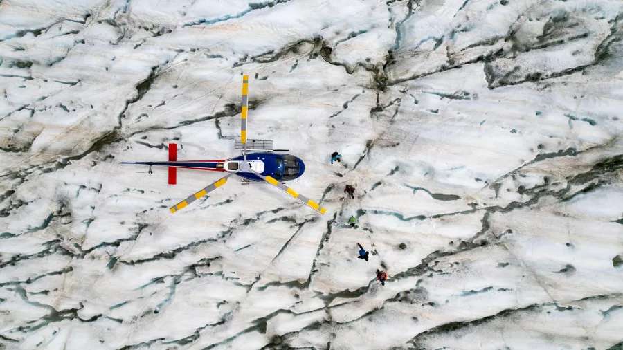 Drone view of helicopter and hikers on the cracked surface of the Tasman Glacier