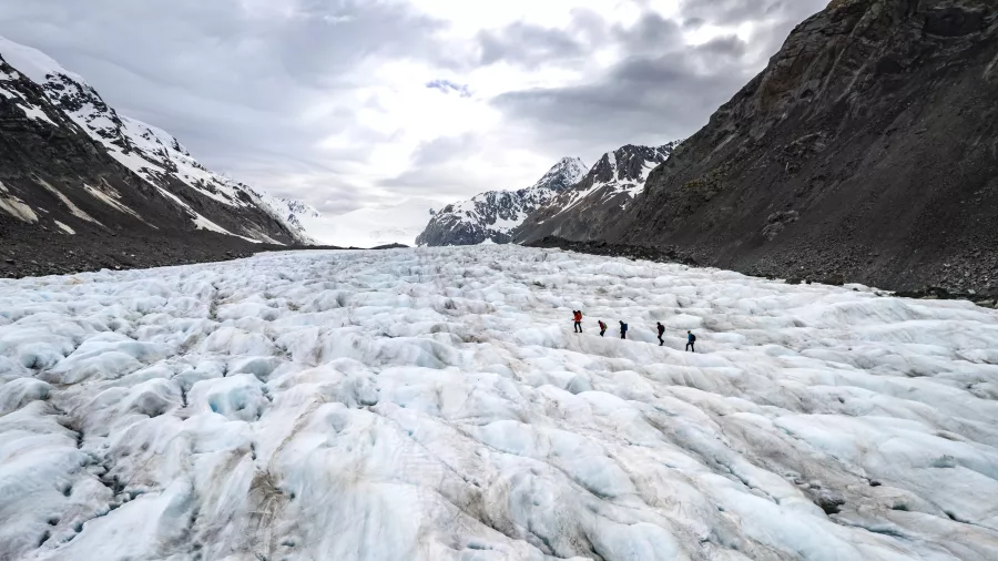 Wide-angle view of hikers crossing the expansive Tasman Glacier