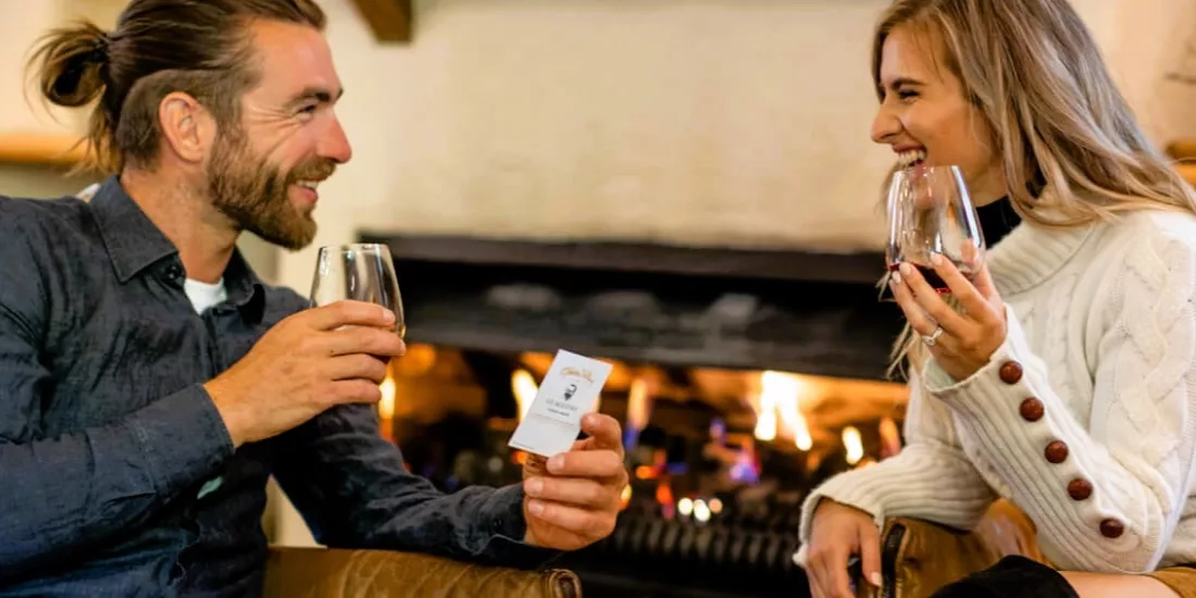 Couple enjoying wine tasting by the fireplace at Gibbston Valley Winery in Queenstown