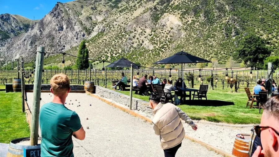 Visitors playing pétanque beside the vines at Brennan Wines in Gibbston Valley