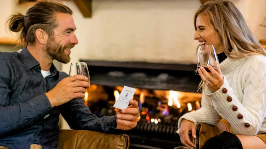 Couple enjoying wine tasting by the fireplace at Gibbston Valley Winery in Queenstown