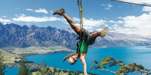 Woman ziplining upside down above Lake Whakatipu on Ziptrek Queenstown’s longest zipline