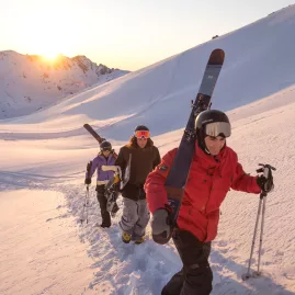 Skiers hiking uphill with gear at sunrise at The Remarkables, Queenstown
