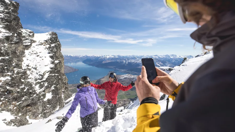 Friends posing for a photo on a snowy lookout at The Remarkables with Lake Wakatipu in the background