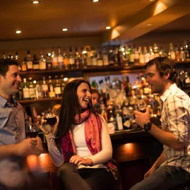 Group of friends enjoying wine at a cosy bar in Queenstown after a day on the slopes
