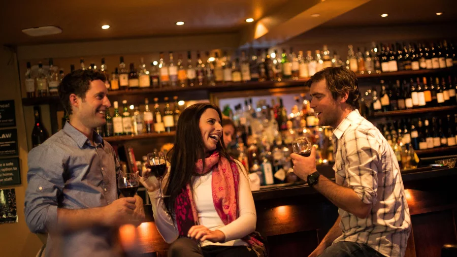 Group of friends enjoying wine at a cosy bar in Queenstown after a day on the slopes