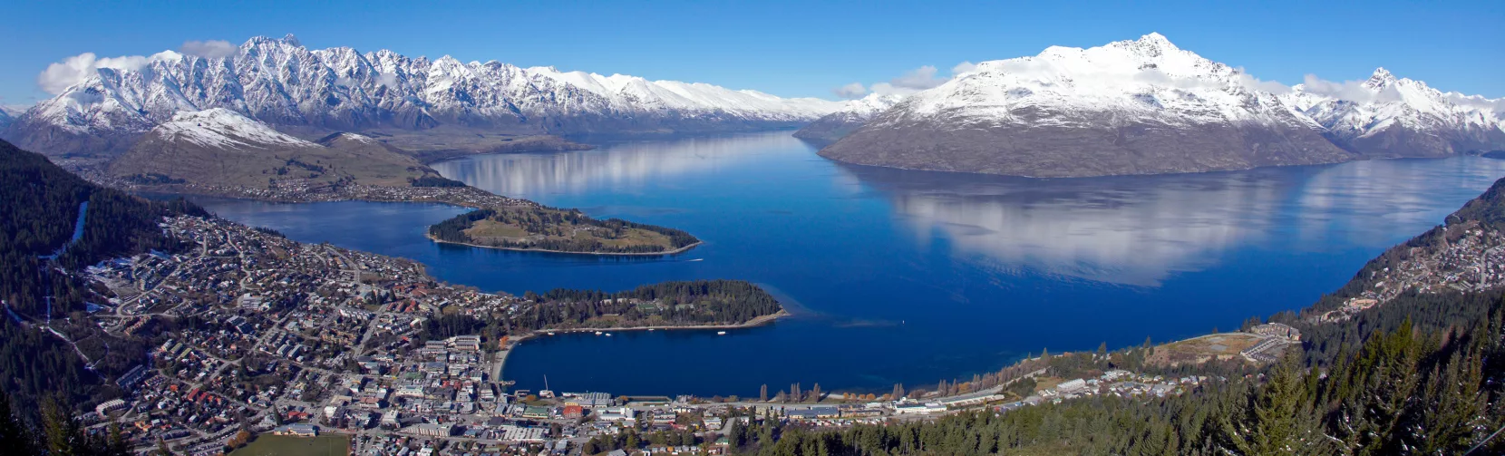 Aerial view over Queenstown with Lake Wakatipu and surrounding snow-covered peaks