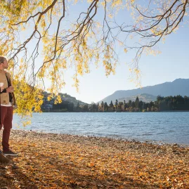 Couple walking along Queenstown Bay Beach during autumn in Otago