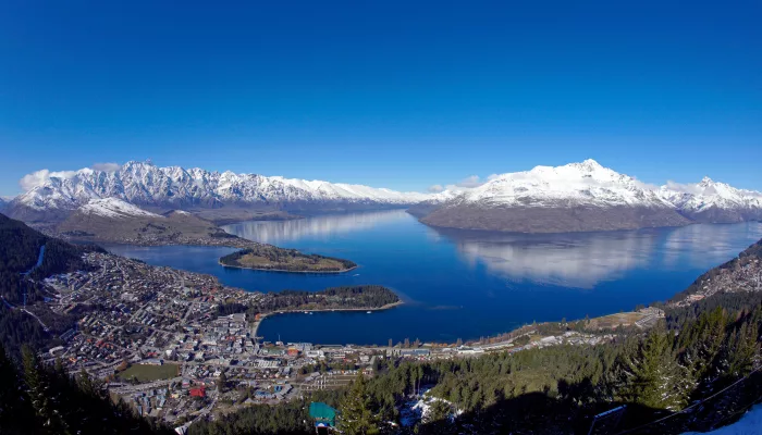 Aerial view over Queenstown with Lake Wakatipu and surrounding snow-covered peaks